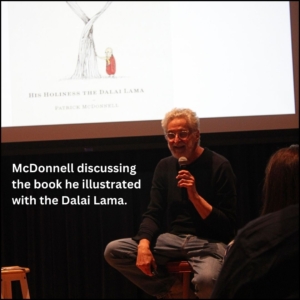 Patrick McDonnell seated on a stool discussing the book he illustrated for the Dalai Lama as the cover is on the projection screen behind him.