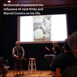 Curator Charles Viera on the left stool next to Patrick McDonnell on the right stool. The slide on the projection shows art by Jack Kirby which heavily influenced McDonnell throughout life.